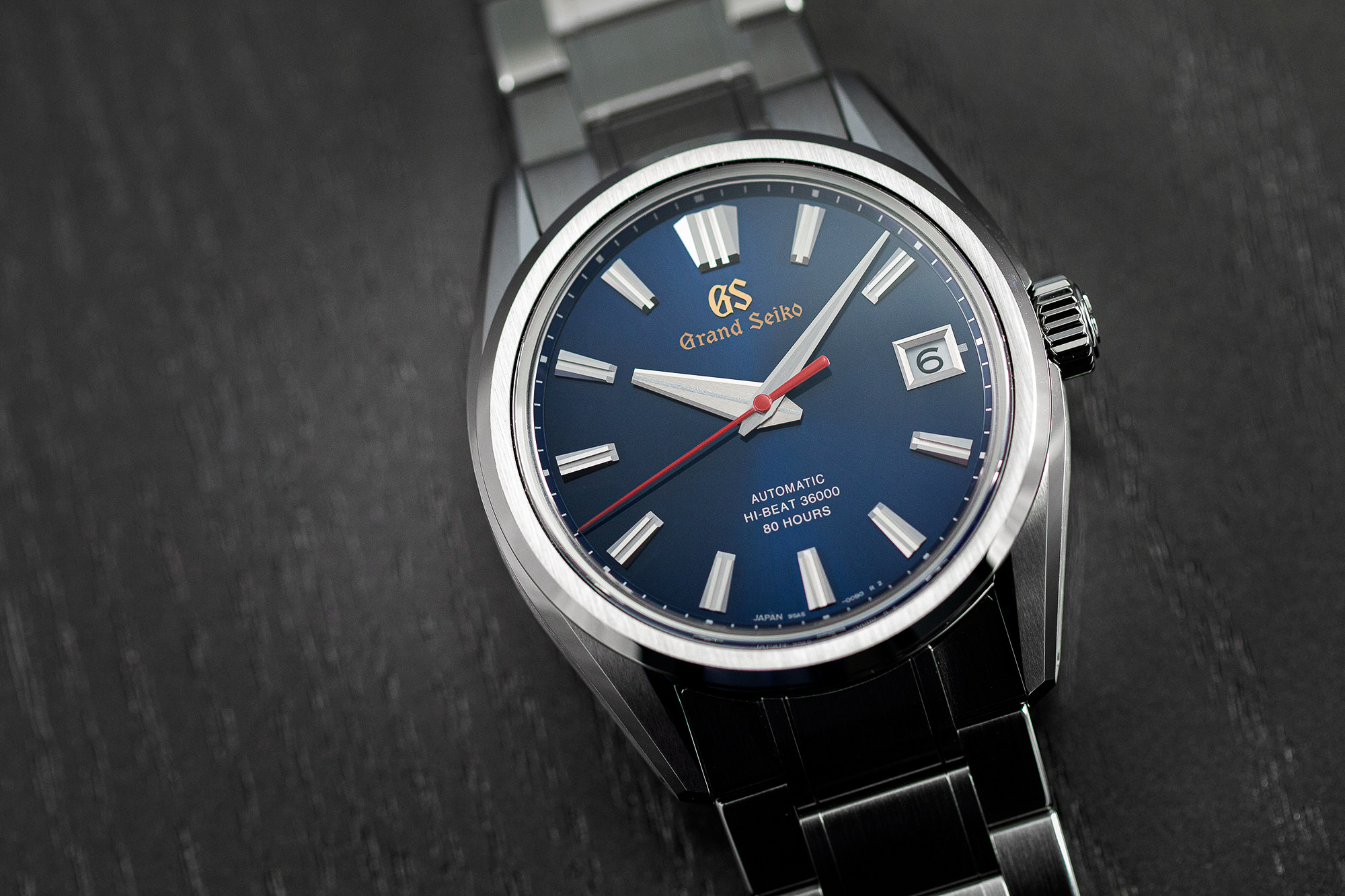 Grand Seiko SLGH003 wristwatch with a blue dial and red accents on a tabletop.